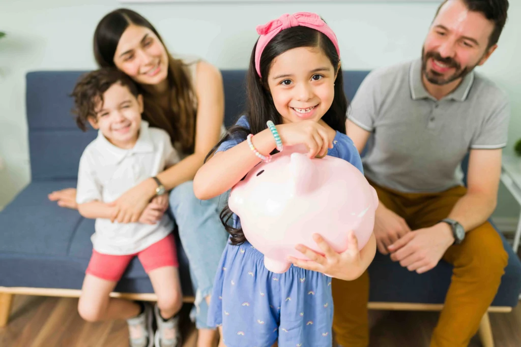 Niña con su familia, ingresando dinero a la Alcancía